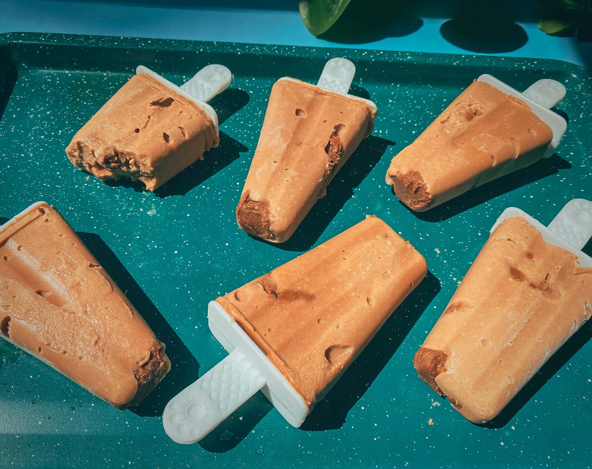 Chocolate brownie popsicles on a teal baking pan