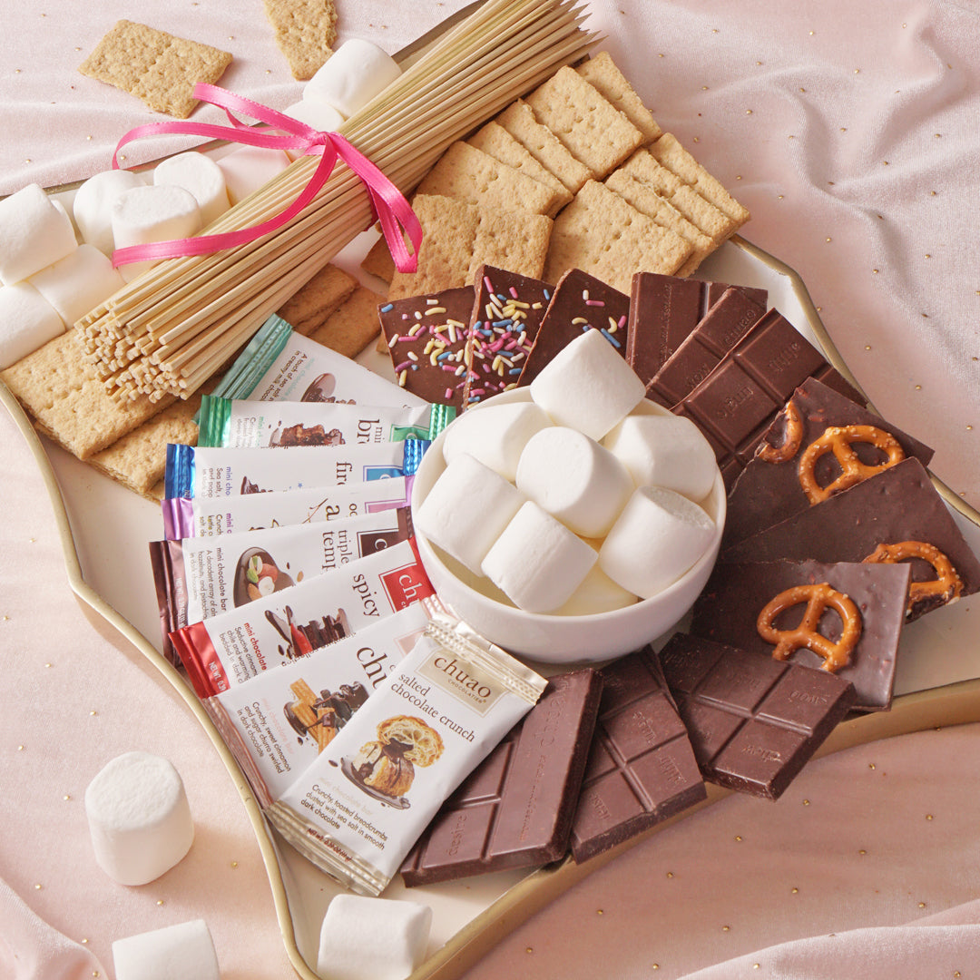 A spread of mini chocolate bars, marshmallows, graham crackers and skewers depicting a warm and cozy feeling