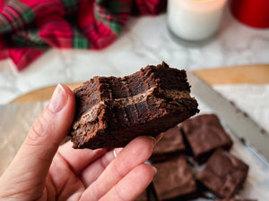 A square of a gingerbread brownie with a bite taken against a seasonal backdrop