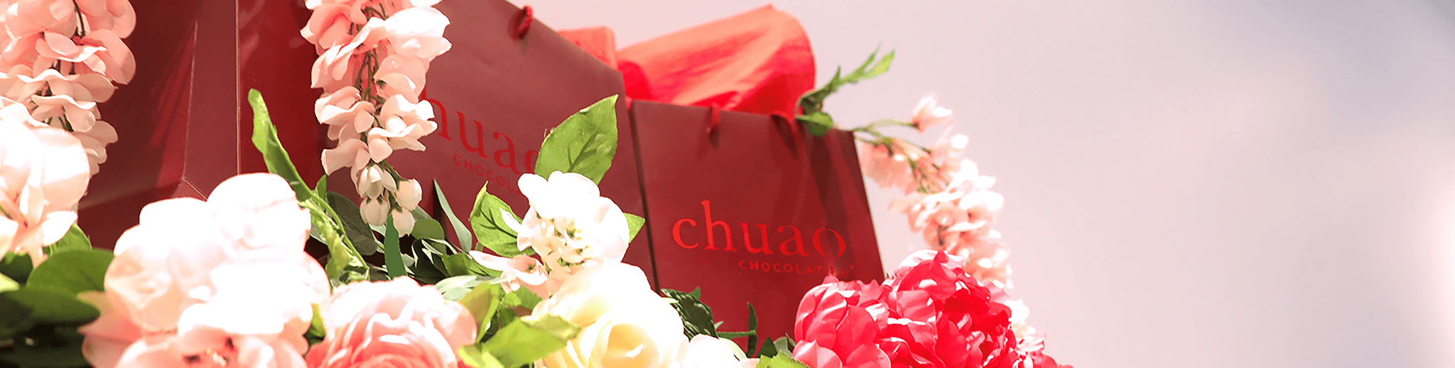 Chuao gift bags in a floral bed and bright light.