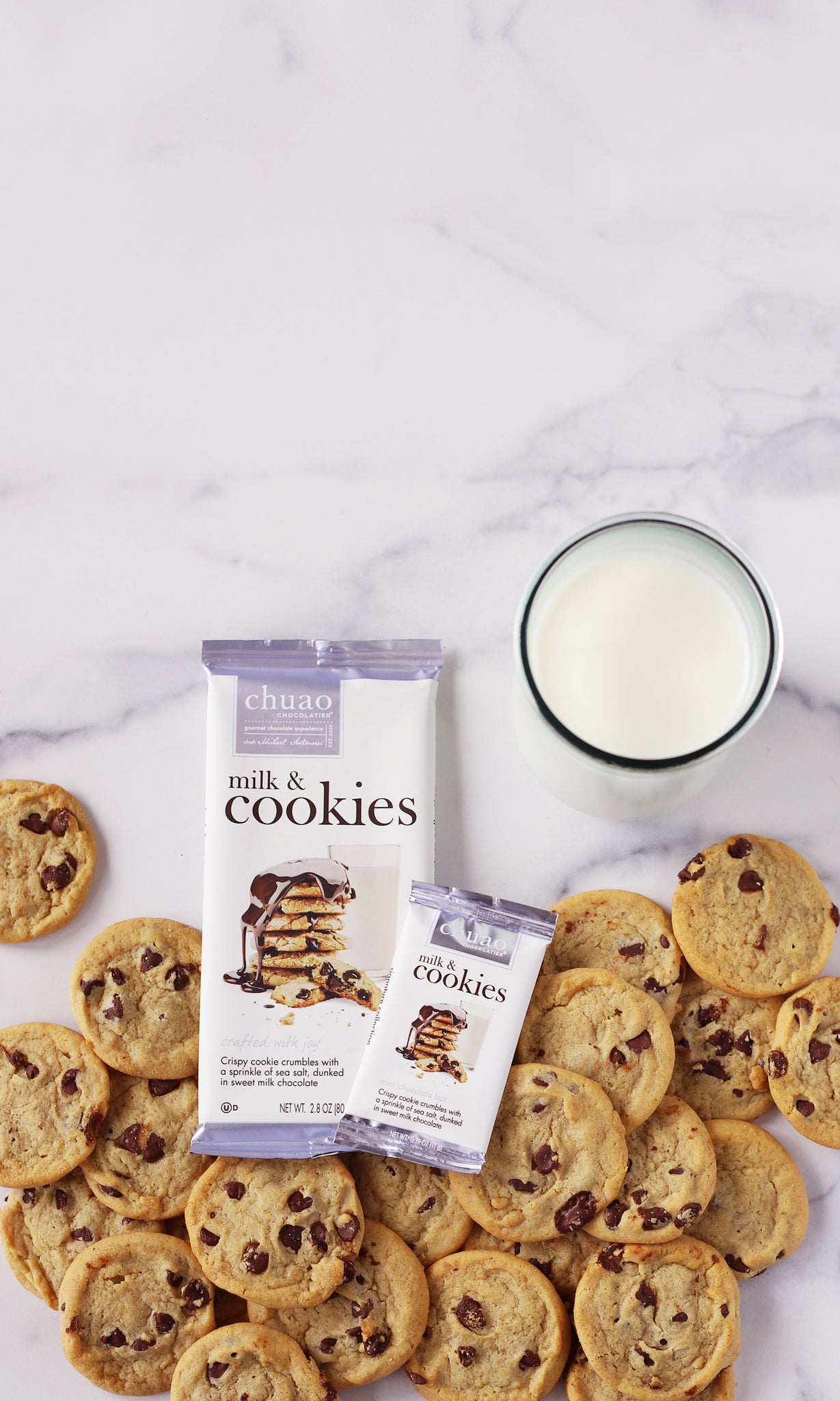 milk and cookies chocolate bar in 2.8 and 0.39 oz. with chocolate chip cookies and glass of milk on marble background